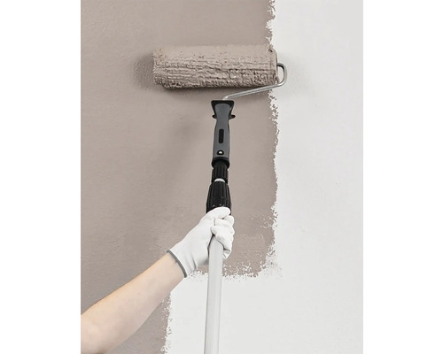 Person målar vägg med färgroller och teleskopstång