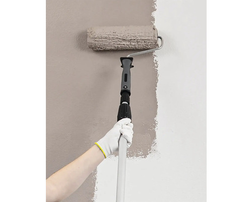 En person målar en vägg med en färgroller på ett teleskopskaft.