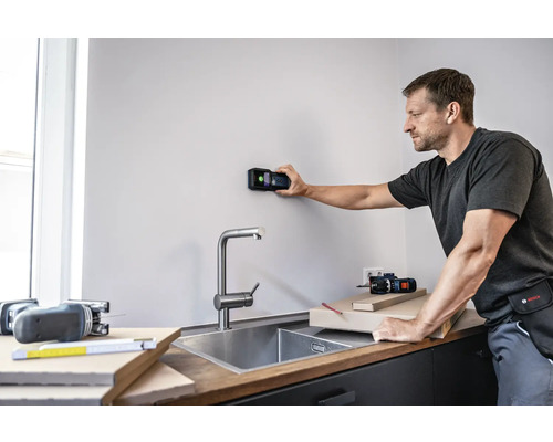 Man använder en digital detektor på en vägg i ett kök.