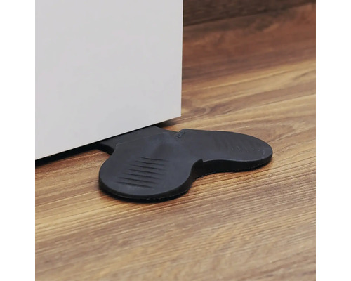 Svart dörrstopp i gummi håller en dörr öppen.