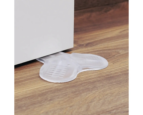 Transparent dörrstopp av plast under en dörr på ett trägolv