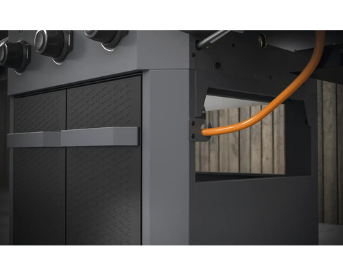 Detaljvy av en gasolgrill med skåpelement och gasledning.