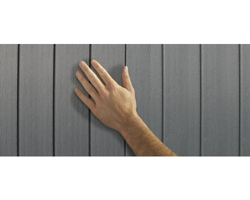 Hand berör grå fasadbeklädnad av plast