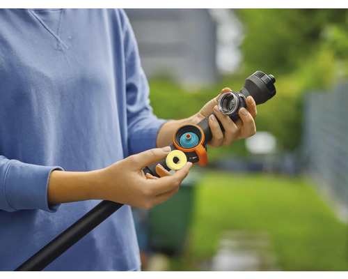 En person ansluter en trädgårdsslangkoppling till en trädgårdsslang