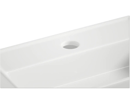 Detaljvy av ett vitt tvättställ med kranhål