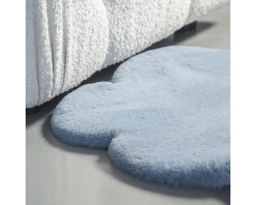 Blå, molnformad matta bredvid en soffa.