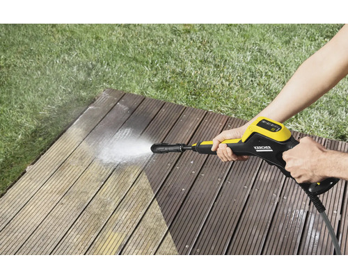 En person rengör en träterrass med en Kärcher högtryckstvätt.