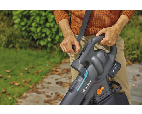 En person fäster en Gardena batteridriven lövsug med axelrem