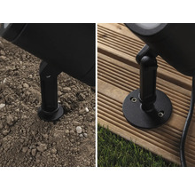 Detaljbild av en utomhuslampa med jordspett och monteringsplatta på mark och träterrass
