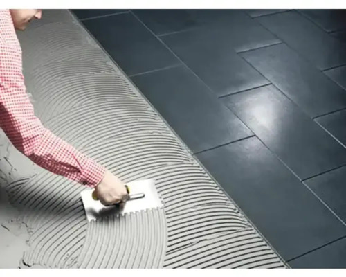 Plattsättare applicerar kakelfix med en tandspackel