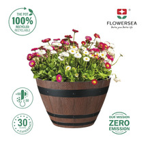 Blomkruka i träfatlook med blommor, med symbolen 100 procent återvinningsbar, Flowersea logotypen och symbolerna för temperaturbeständighet och 30 års erfarenhet