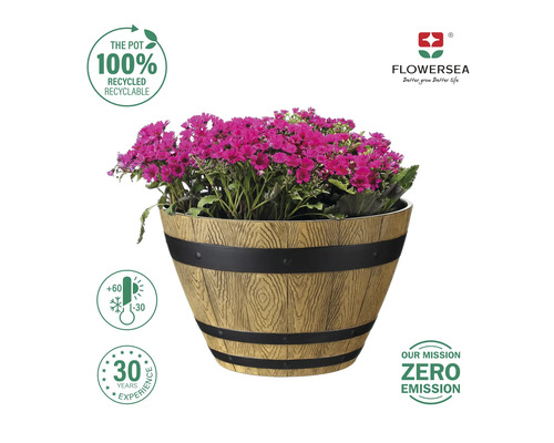 Blomkruka i träfatlook med lila blommor och indikationerna 100 procent återvunnet, temperaturbeständigt, 30 års erfarenhet, nollutsläpp och Flowersea-logotyp