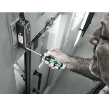 En man använder en skruvmejsel för att dra åt en skruv på en elektronisk komponent.