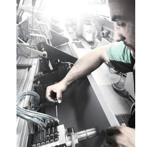 En man som reparerar en maskin med en skruvmejsel.