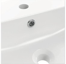 Detaljvy av ett vitt tvättställ med kranhål och överfyllnadsskydd