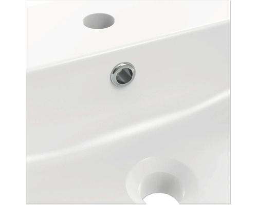 Detaljvy av ett vitt tvättställ med kranhål och överfyllnadsskydd