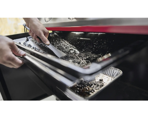 Rengöring av en grill med en skrapa för att ta bort rester