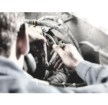 Mekaniker med skiftnycklar reparerar en motor