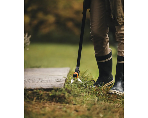 Person använder en grässax med handtag för gräsmatteskötsel