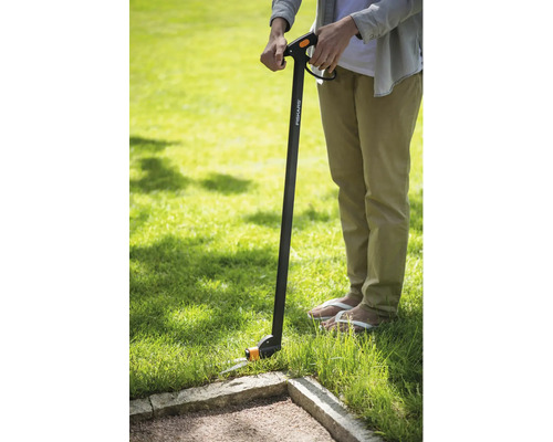 Person använder en Fiskars grässax för att klippa gräskanter