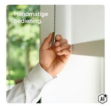 Manuell manövrering av rullgardin med kedjedrag och metallhandtag vid ett fönster (Image AI modified or generated)