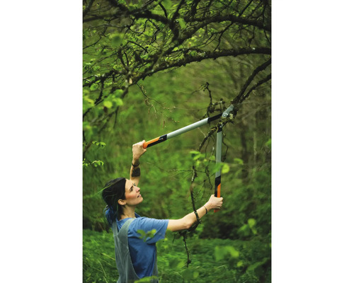 Kvinna beskär grenar med en grensax i trädgården