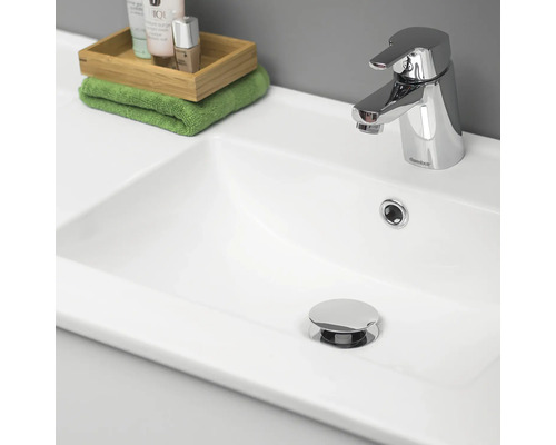 Bild av ett handfat med kran, kosmetika och handduk