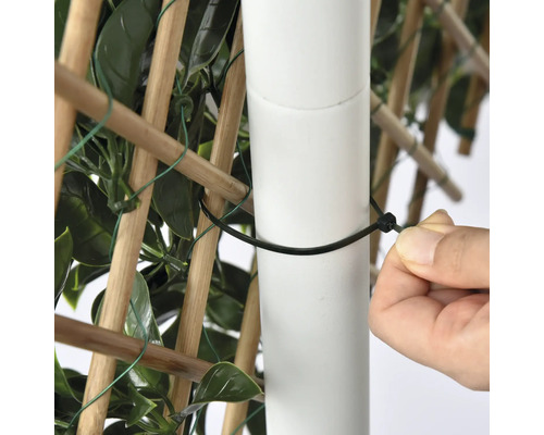 Närbild av en person som fäster en insynsskyddsskärm på en stolpe med en buntband.