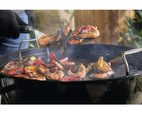 Grillade räkor och paprika vänds med en grillspatel.