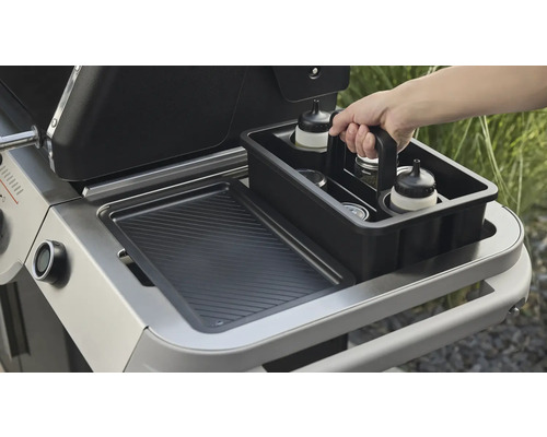 Detaljvy av en grill med behållare för grilltillbehör.