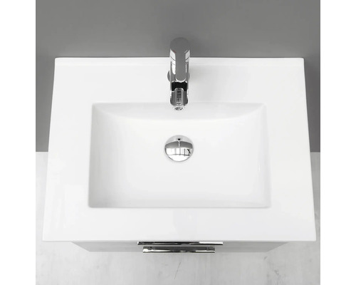 Överifrånvy av ett keramiskt handfat med armatur och överlopp