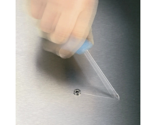 En hand använder en doseringsapplikator bredvid en skruv.