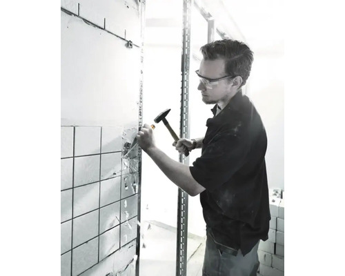 Hantverkare tar bort kakel från en vägg med en hammare och mejsel