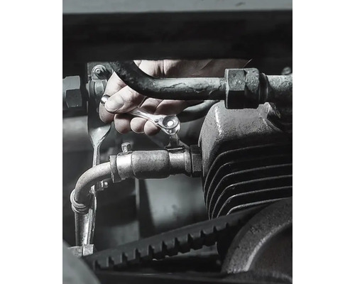 Hand drar åt skruv på motor med spärrnyckel