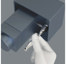 En hand använder en spärrnyckel för att dra åt en skruv.