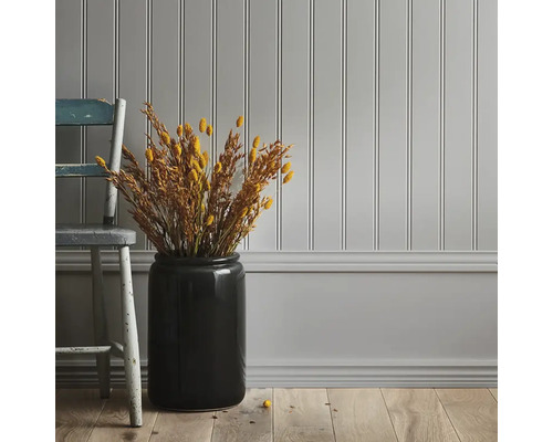 Dekorativ väggdesign med paneler, kombinerat med trägolv och en vas med torkade blommor
