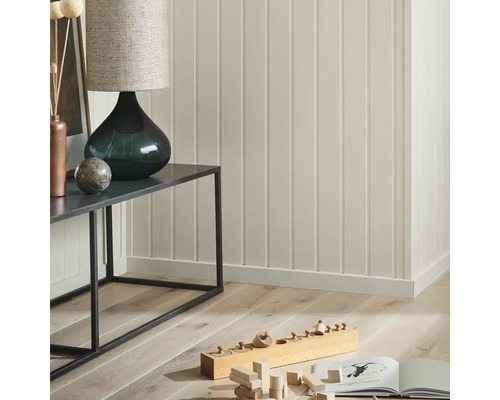 Detaljvy av ett rum med väggpaneler, konsolbord, lampa och barnleksaker