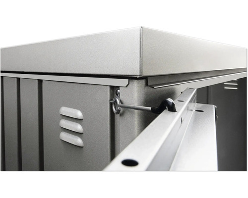 Detaljvy av ett trädgårdsskjul med metallelement, ventilationsöppningar och en låsmekanism.