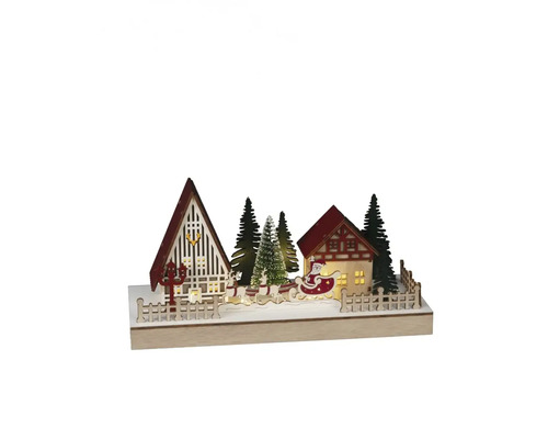 Dekorativ julscen med hus, träd och jultomten i en släde.