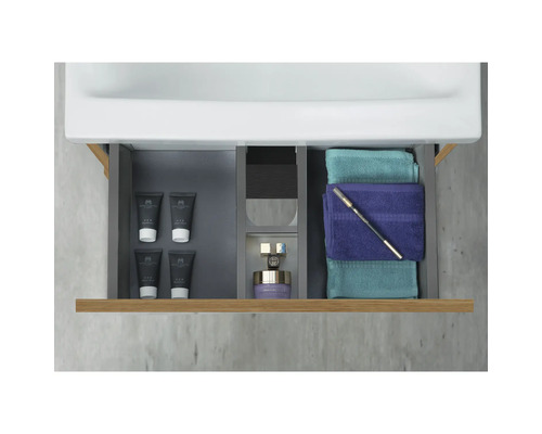 Öppen låda i ett tvättställsskåp med kosmetika och handdukar