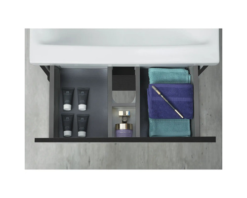 Badrumsskåp med öppen låda, fylld med kosmetiska produkter och handdukar.