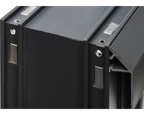 Detaljbild av en svart aluminiumprofil med magnetfästen och skruvhål.