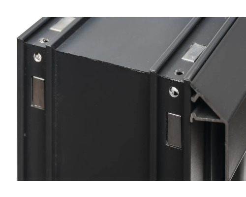 Detaljvy av en svart aluminiumram med magneter och borrade hål.