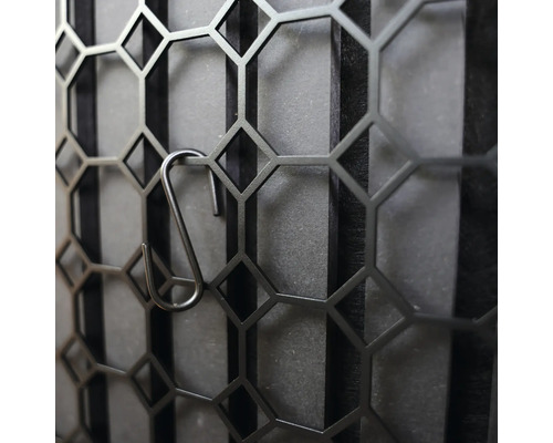 Dekorativ metallvägg med hexagonalt mönster och krokar