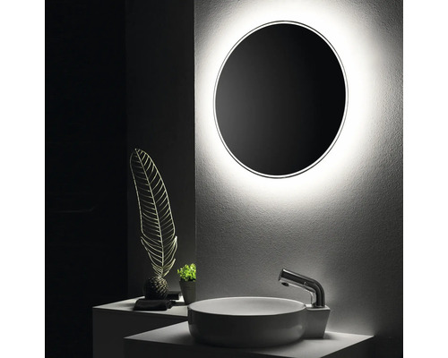 Modernt badrum med rund spegel, tvättställsskål och dekorativa element för en stilfull atmosfär.