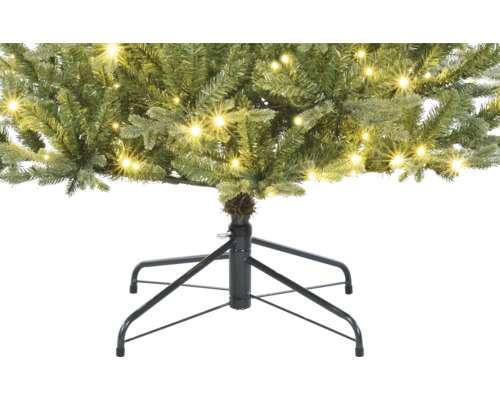 Detaljbild av en konstgjord julgran med belysning och ett julgransstativ