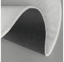 Detaljvy av en rund matta med lugg och halkfri baksida