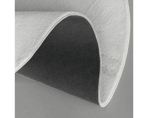 Detaljvy av en rund matta med lugg och halkfri baksida