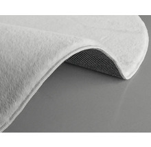 Detaljvy av en vit matta med lugg och vävd baksida