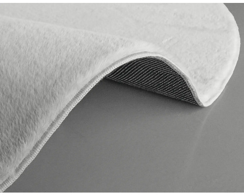 Detaljvy av en vit matta med lugg och textilbaksida